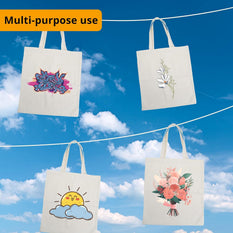 Four tote bags with designs hanging against a blue sky.
